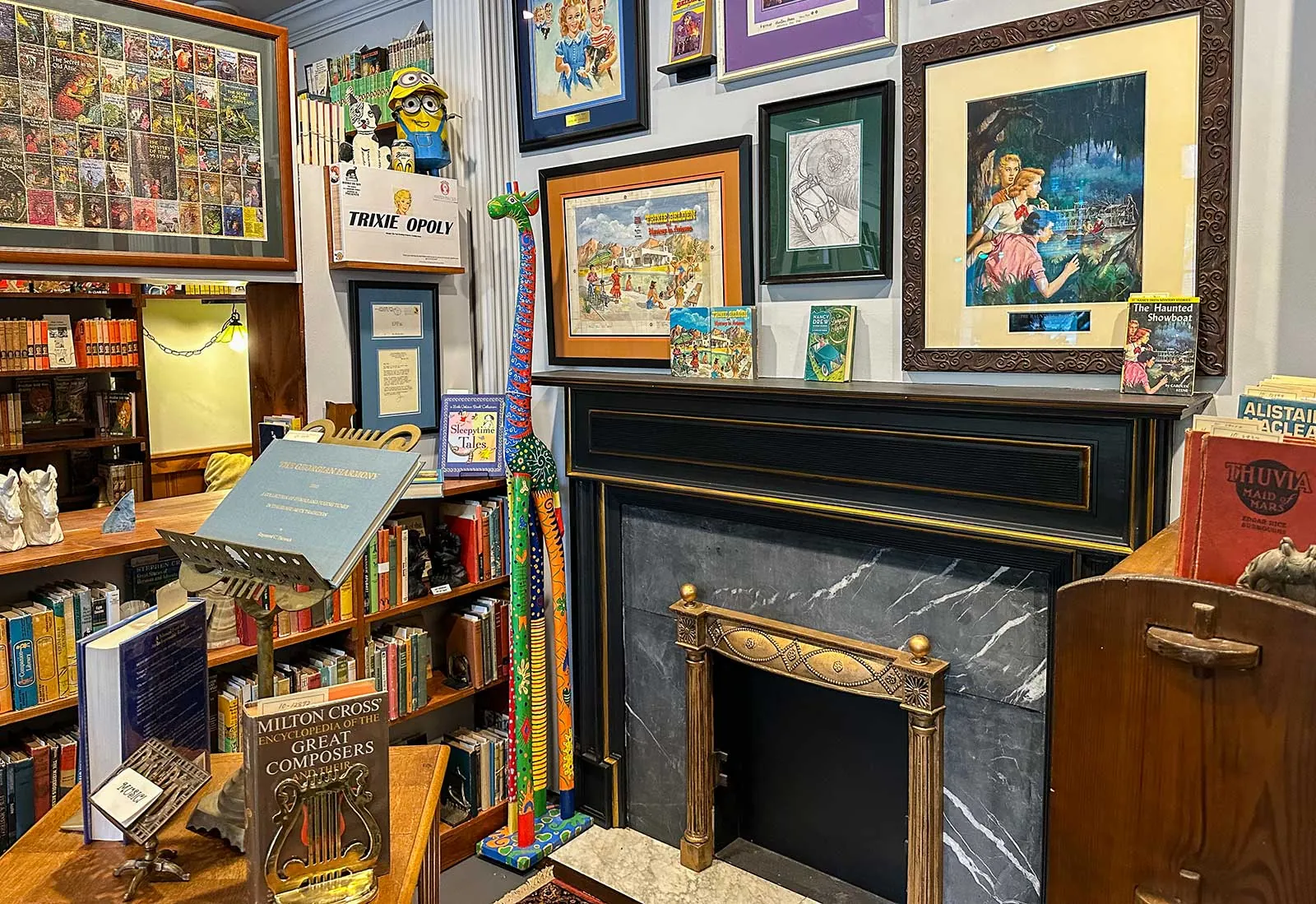 Vintage book cover art at Books on Bay, Savannah Framed book cover art and vintage series books around a marble fireplace at Books on Bay in Savannah, GA