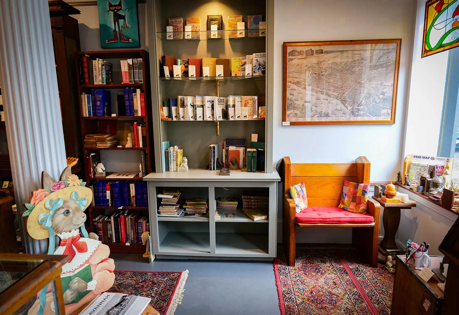 Books on Bay used bookstore interior, Savannah A reading nook with a wooden bench, bookshelves and a framed antique map of Savannah at Books on Bay