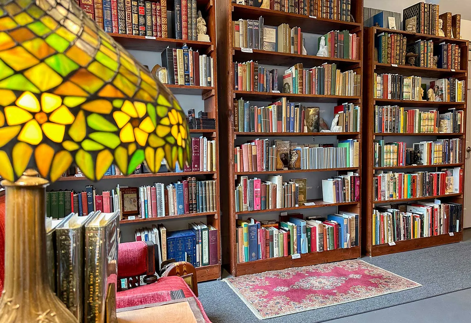 Vintage and antique books at Books on Bay, Savannah Tall wooden shelves of vintage and antique books behind a stained-glass lamp at Books on Bay in Savannah, GA